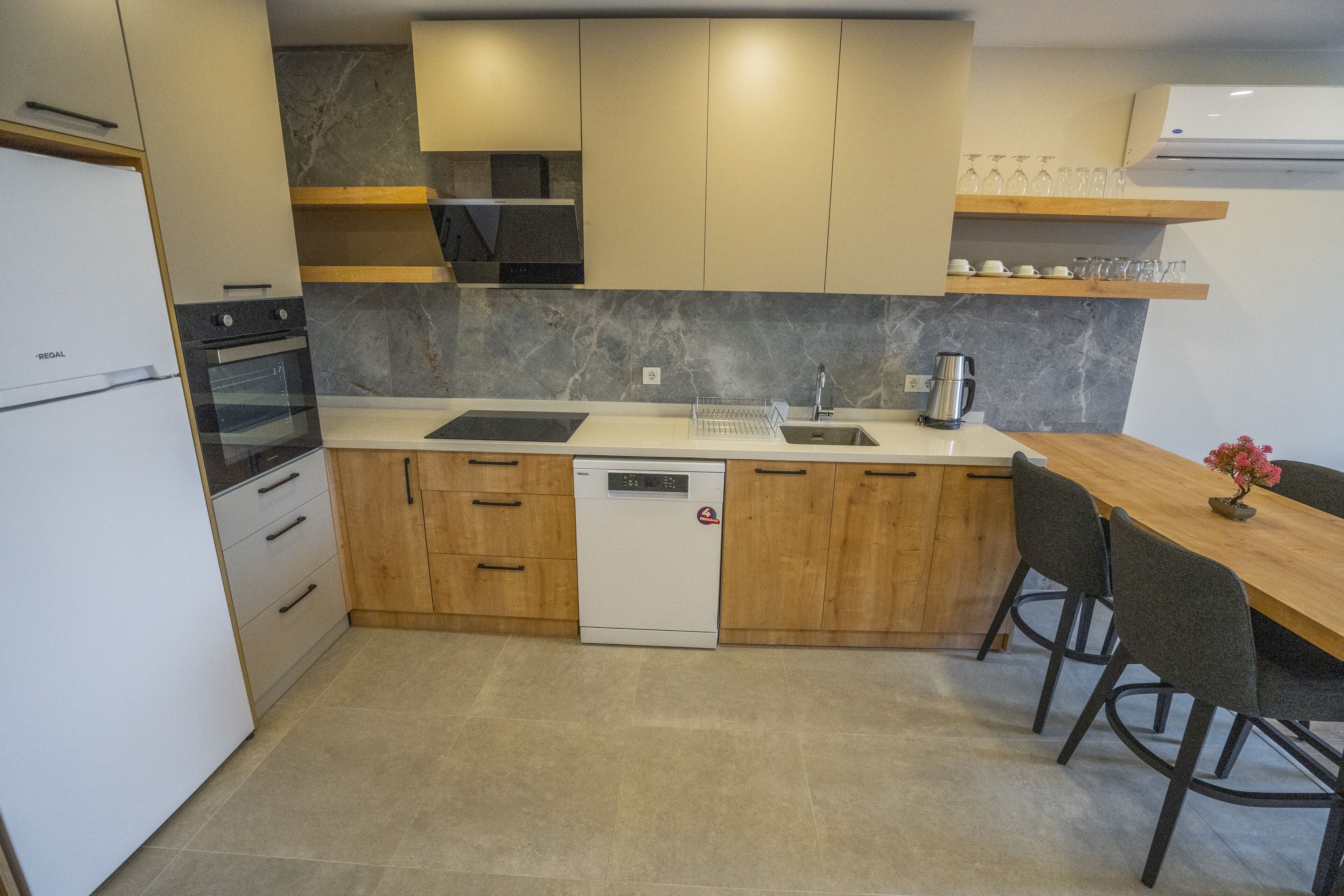 A modern kitchen with a dishwasher, oven, and wooden cabinets.