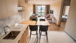 A modern kitchen with a built-in oven, a sink, and a dining area with two chairs and a table. - Let'stay Marine Homes (Antalya)