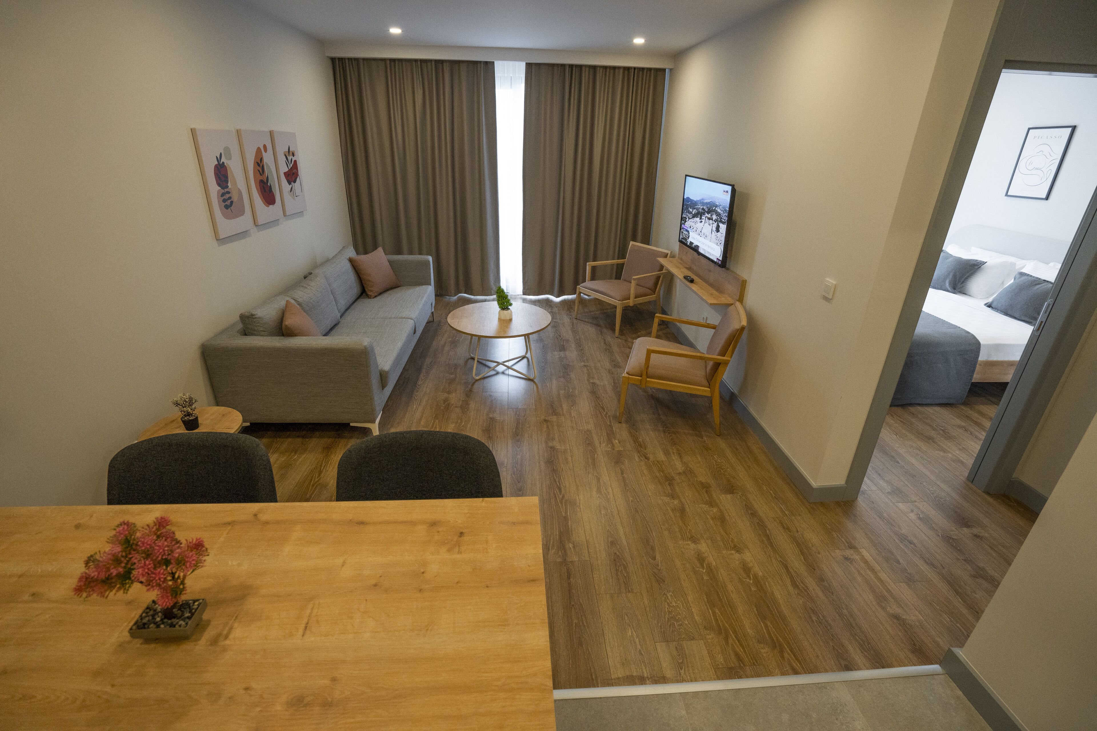 A modern living room with a sofa, chairs, a coffee table, and a TV.