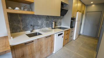 A modern kitchen with wooden cabinets, a white countertop, a built-in dishwasher, and a stainless steel coffee maker.