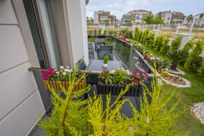 A balcony with a glass railing, potted plants, and outdoor furniture. - Let'stay Marine Homes (Antalya)