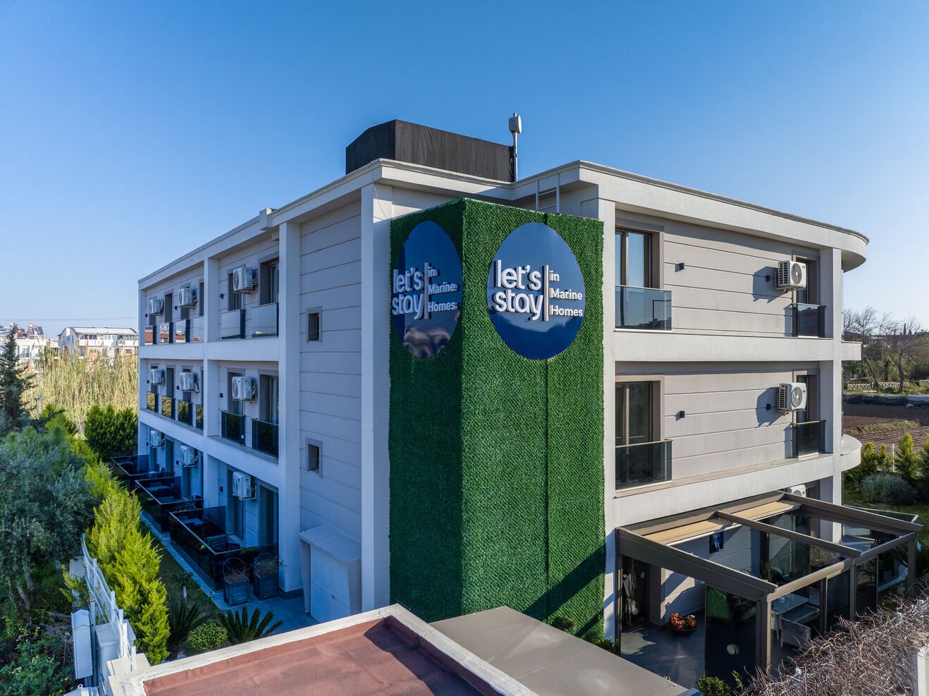 A modern building with a green vertical garden and multiple air conditioning units.