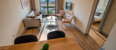A modern living room with a sofa, chairs, a coffee table, and a TV.