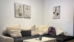 A modern living room with a sofa, a coffee table, and two framed floral artworks on the wall.