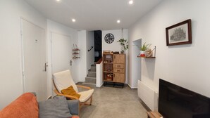 Ein modernes Wohnzimmer mit einer Couch, einem Fernseher, einer Treppe und einer Wanduhr.