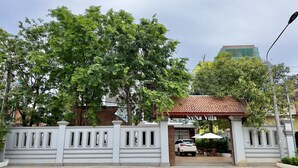 A gated entrance with a white fence, a covered patio area, and a white car parked inside.