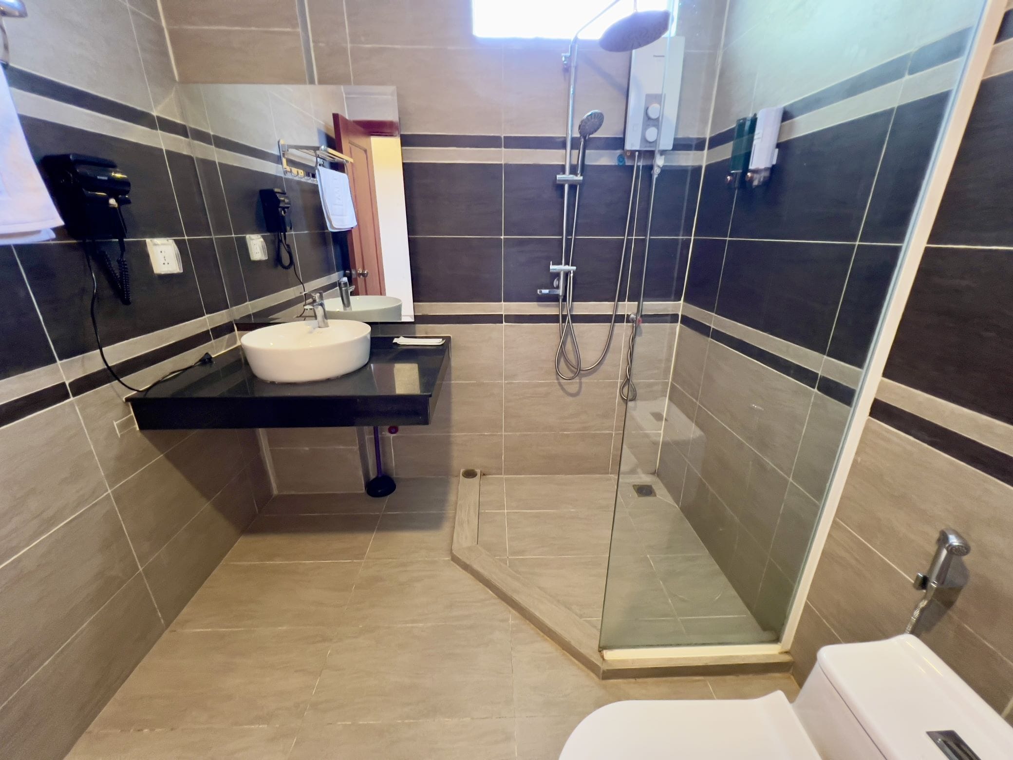 A modern bathroom with a glass-enclosed shower, a sink with a mirror, and a toilet.