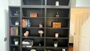 Een zwarte boekenkast met meerdere planken, waarvan sommige boeken en decoratieve objecten bevatten.