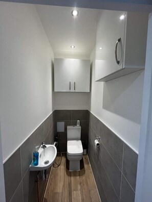 A compact bathroom with a toilet, sink, and cabinet. - Inviting & Spacious 3BD Flat - Shadwell (London)