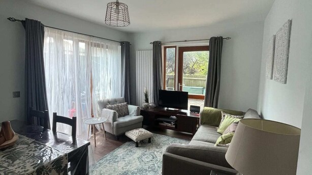 Een moderne woonkamer met een bank, een salontafel, een televisie en een eethoek met een tafel en stoelen.