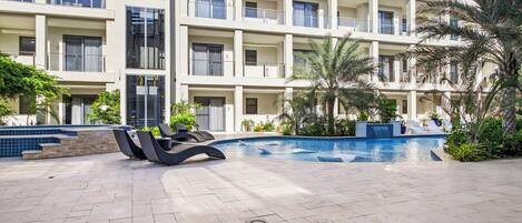 A modern hotel with a pool area, outdoor seating, and a landscaped garden.