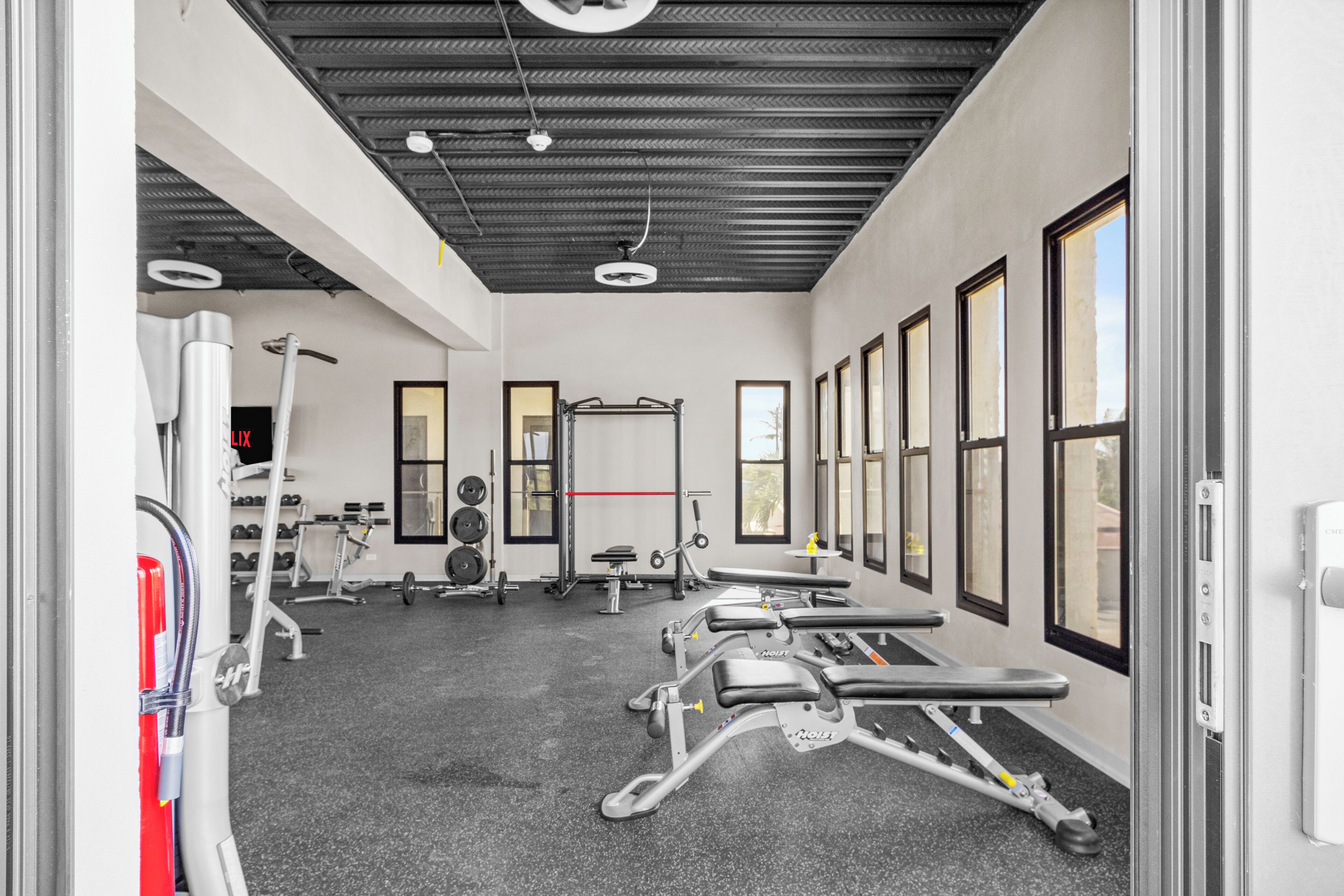 A gym with exercise equipment, a weight rack, and large windows.