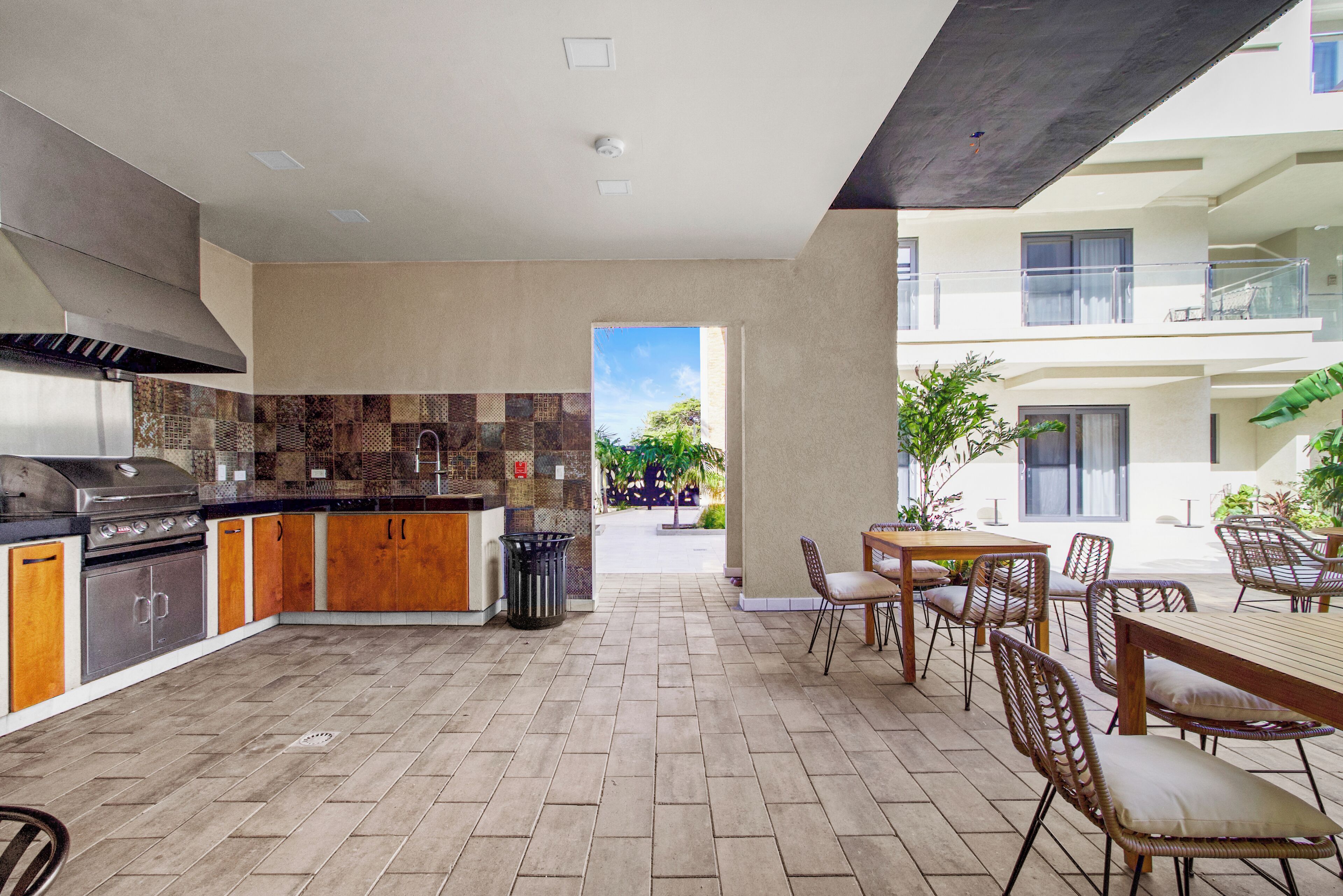 A modern kitchen with a built-in stove and a dining area with wicker furniture.