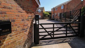 A brick building with a black gate and a post box labeled "POST". - The Coach House At The Gables (Shrewsbury)