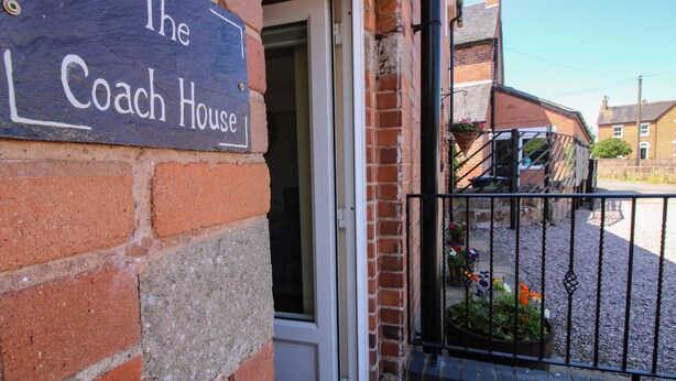 A brick building with a sign reading "The Coach House" and a door leading inside. - The Coach House At The Gables (Shrewsbury)