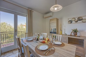 Comedor con una mesa preparada para cuatro, una botella de vino y una bandeja de fruta.