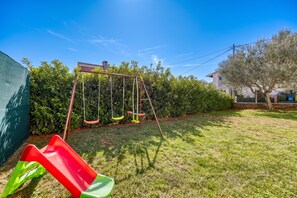 A backyard with a swing set, a slide, and a well-maintained lawn.