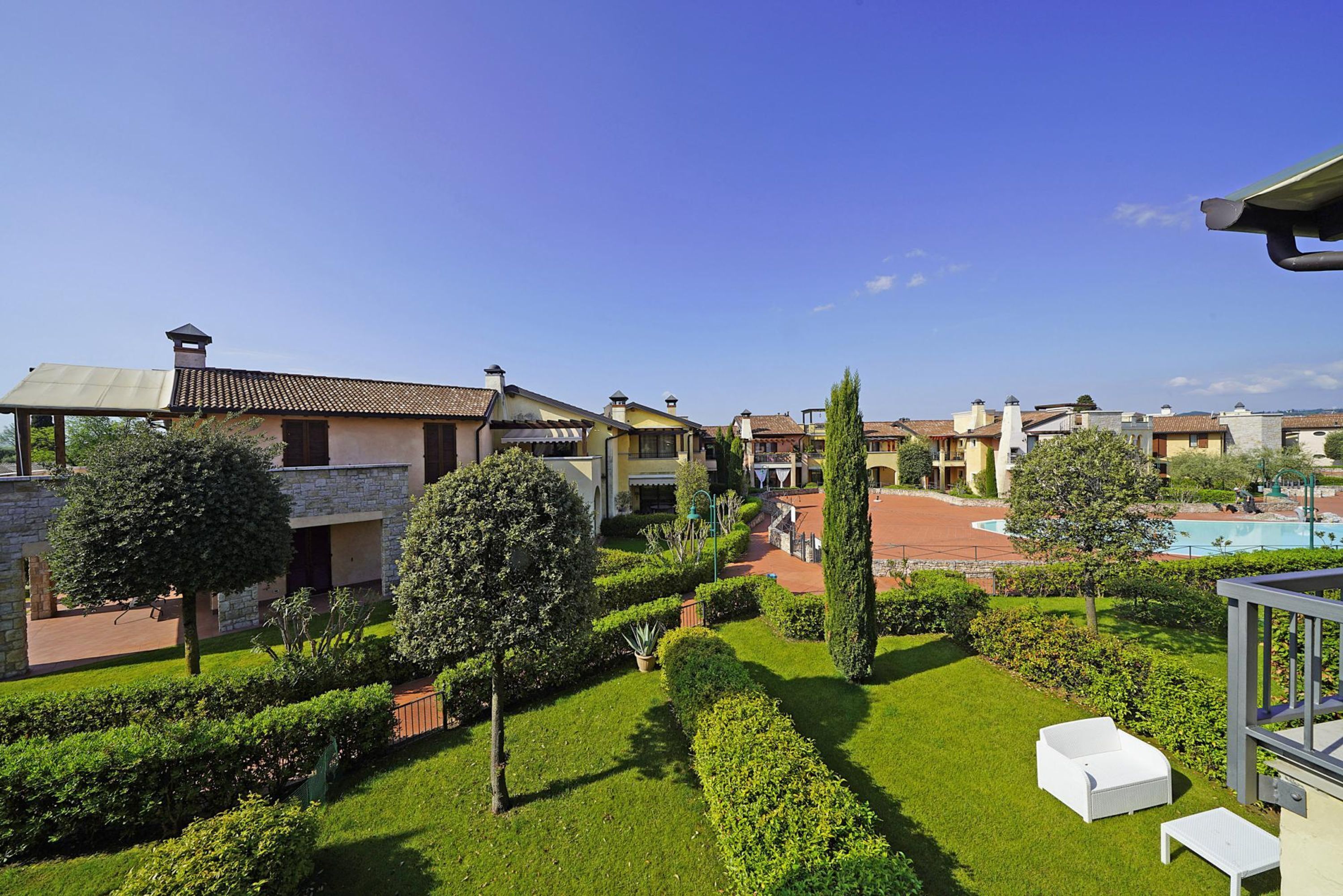 Un cortile con siepi curate, una piscina e diversi edifici dai differenti stili architettonici.