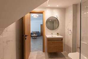 Une salle de bain moderne avec un meuble-lavabo en bois, un miroir rond et une cabine de douche en verre.