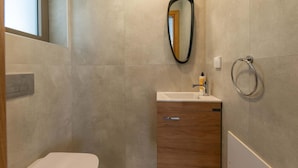 Ein modernes Badezimmer mit einem Holzkabinent, einem Waschbecken und einem Spiegel.