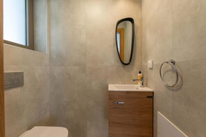 Un baño moderno con un mueble de madera, un lavabo y un espejo.