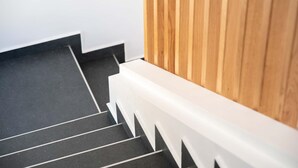 Eine Treppe mit schwarzen Stufen und weißen Geländern, die zu einer Holzwand führt.