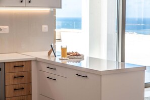 A modern kitchen with white cabinetry, a glass-top island, and a view of the ocean. - Actea Seaview Villa I Free Heated Pool 800m sea (Kissamos)