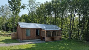 Eine kleine Holzhütte mit einem Metalldach, einer Veranda und einem Kiesweg, der dorthin führt.