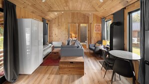 Ein modernes Blockhaus-Interieur mit Holzwänden und -decke, einer Couch, einem Esstisch und einem Fernseher.