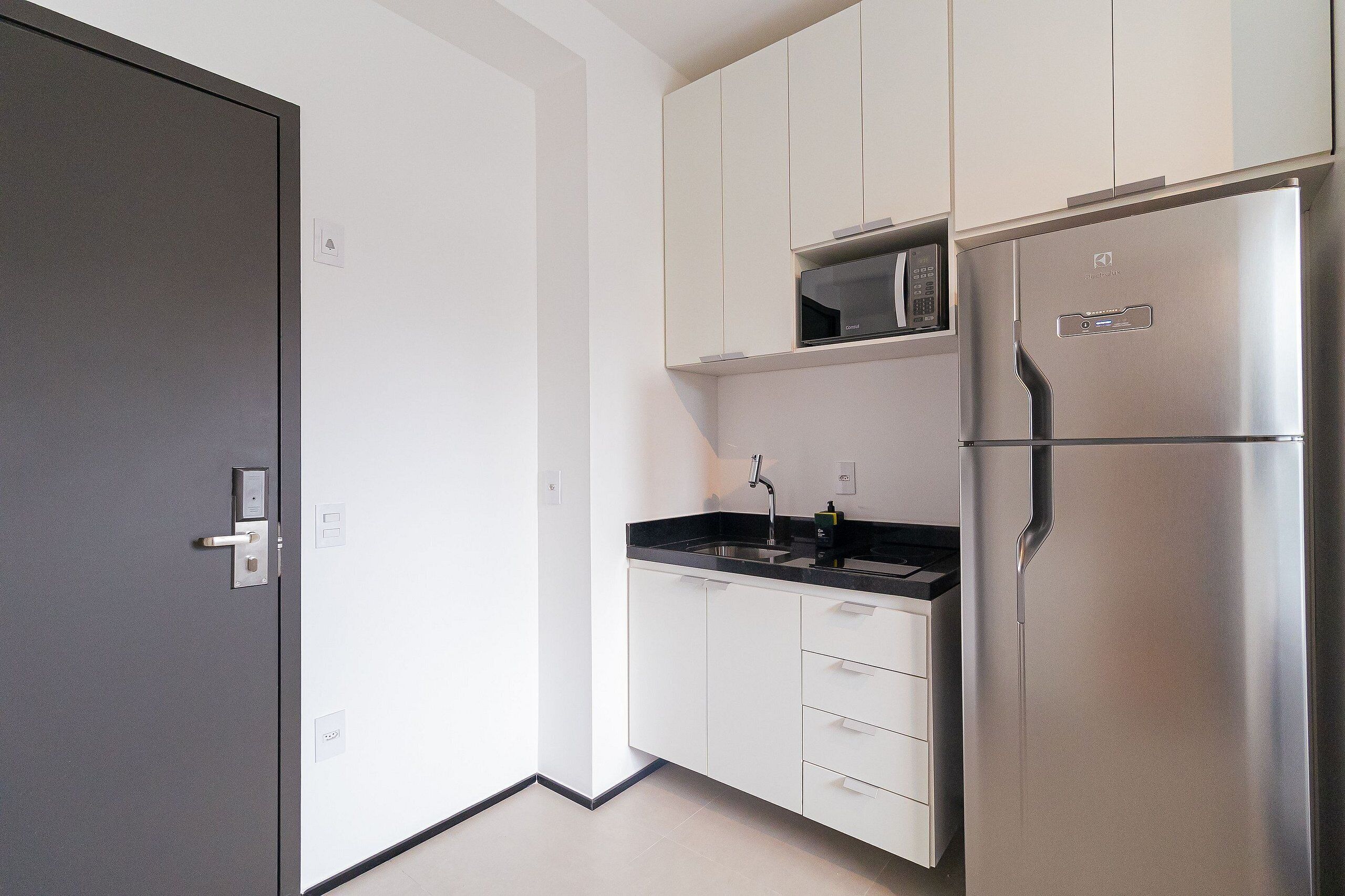A modern kitchen with white cabinets, a stainless steel refrigerator, and a built-in microwave.