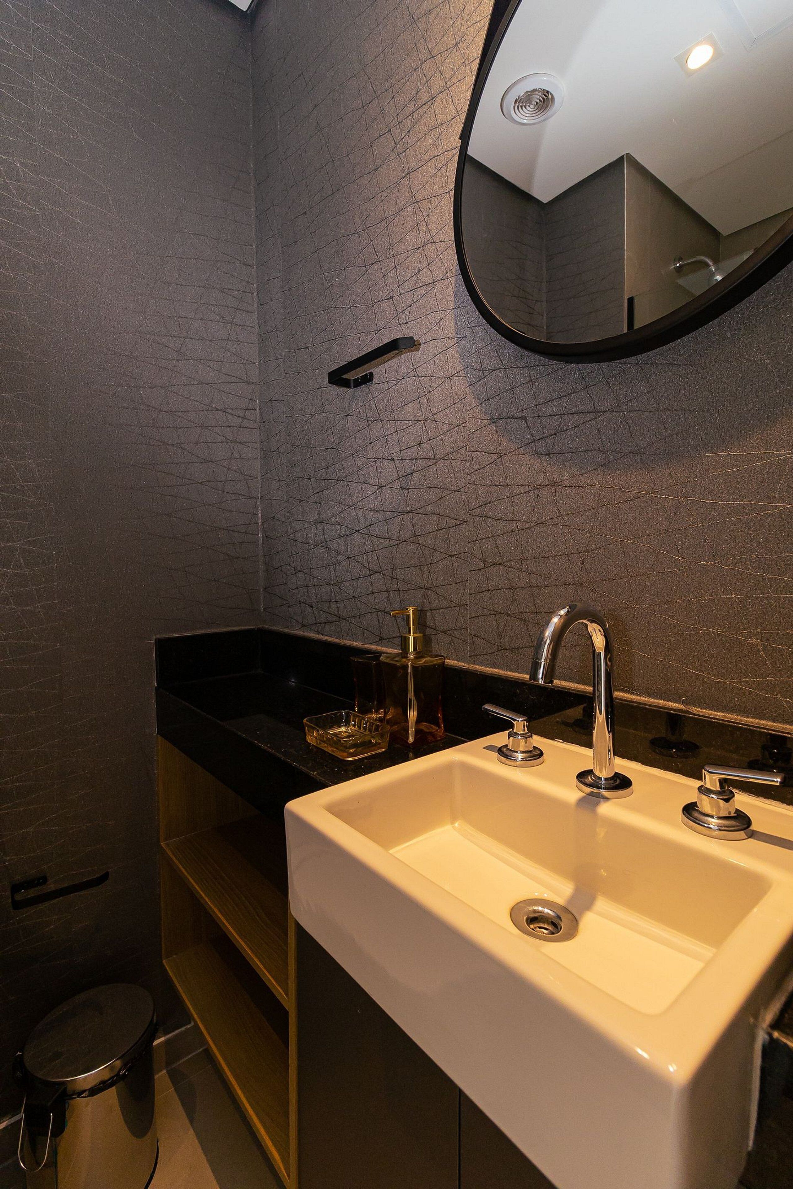 A bathroom with a white sink, black countertop, and a mirror.