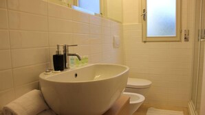 A bathroom with a large vessel sink, a toilet, and a window. - Lovely Apartment in Lignano Sabbiadoro (Lignano Sabbiadoro)