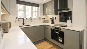 A modern kitchen with a large island, built-in oven, and stainless steel appliances. - The Office (Telford)