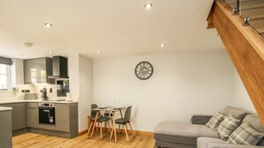 A modern kitchen with a dining area, a gray sofa, and a fluffy rug. - The Office (Telford)