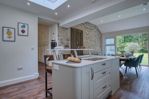 Una cocina moderna con una pared de acento de piedra, una isla integrada y un comedor con vistas al jardín.