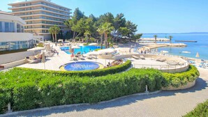 A resort with a pool, beach area, and a building with multiple balconies. - Apartment Near Beach With the Balcony (Podstrana)