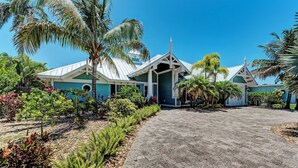 A resort with a paved driveway leading to a building with a green roof and white trim.