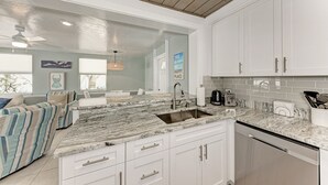 A modern kitchen with white cabinets, a marble countertop, and a built-in dishwasher.