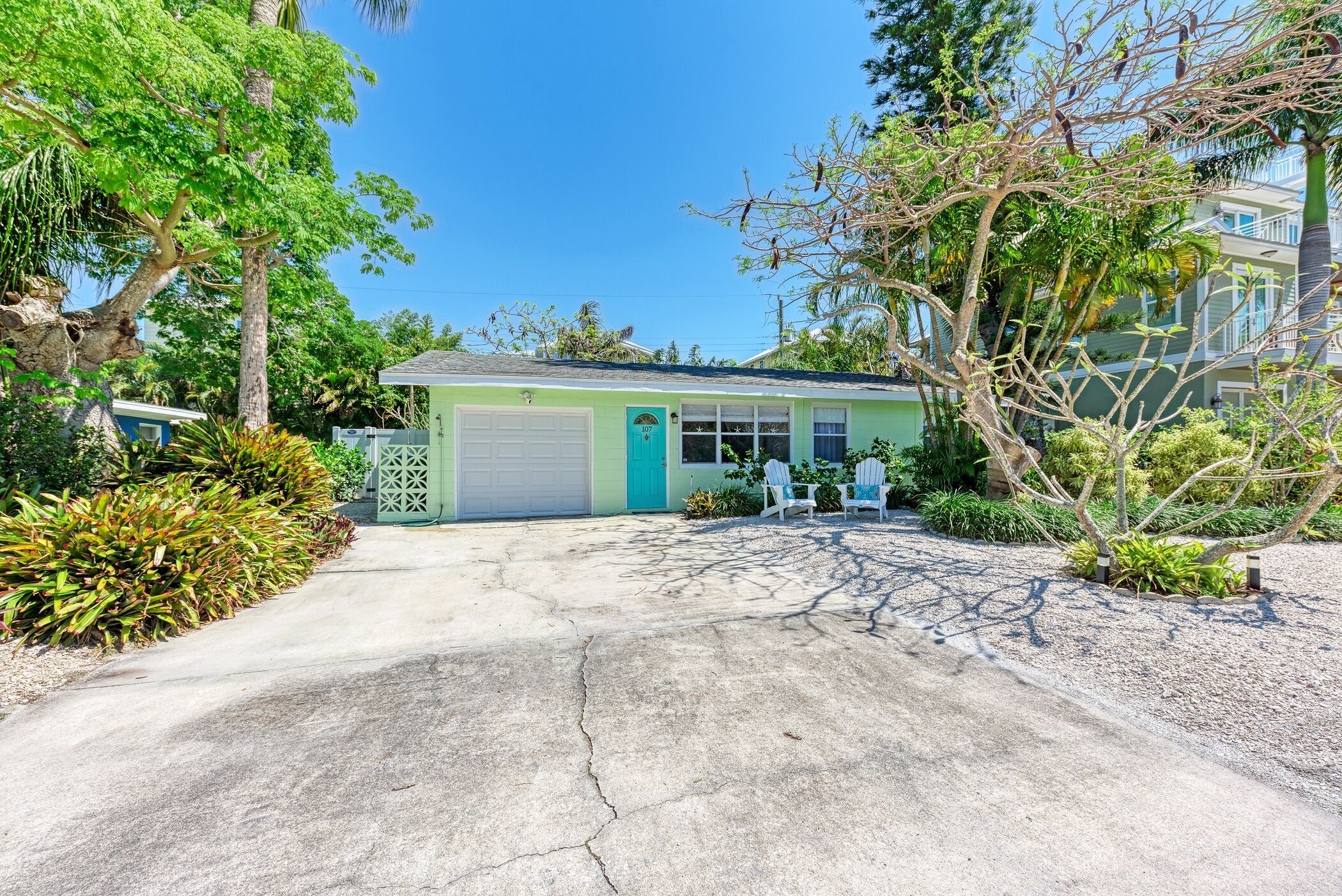 A single-story building with a garage, surrounded by lush greenery and trees.
