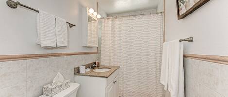 A bathroom with a toilet, sink, and shower curtain.