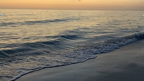 A beach with gentle waves and a clear sky.