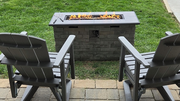 A fire pit with two chairs facing it, a concrete pathway, and a patterned rug. - Perfectly Small House (Xenia)