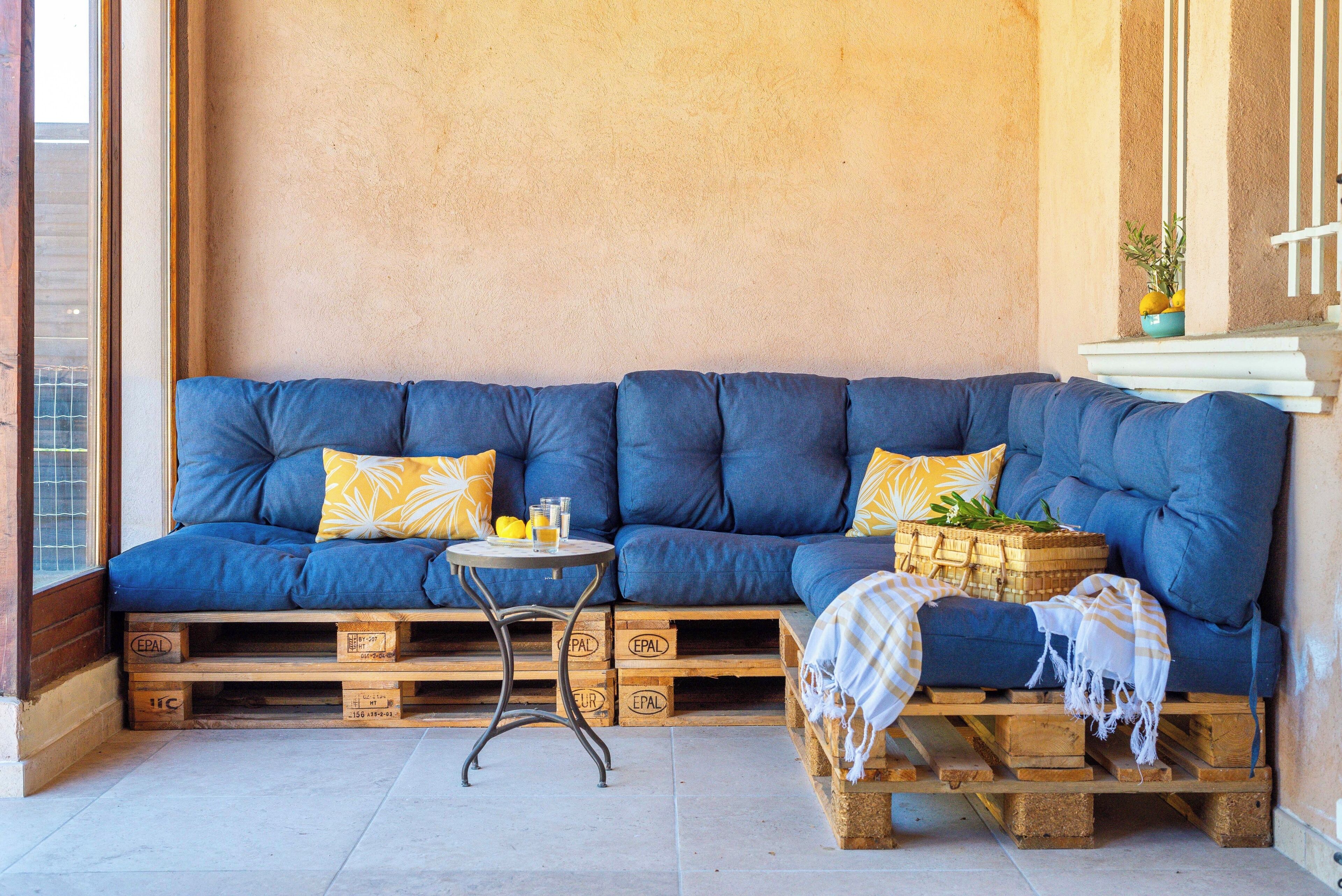 A cozy seating area with a blue sofa, a small round table, and a wooden bench.