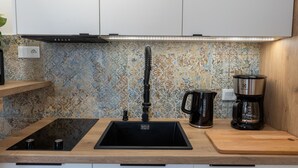 Ett modernt kök med en svart diskho, en kaffebryggare och en bänkskiva i trä.