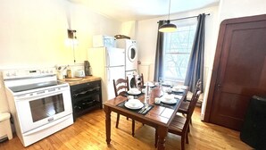 A compact kitchen with a dining area, including a stove, refrigerator, and dining table set for four.