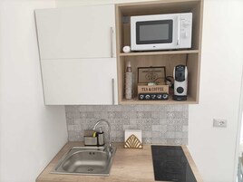 Una cucina con forno a microonde, selezione di tè e caffè e macchina per il caffè sullo scaffale.