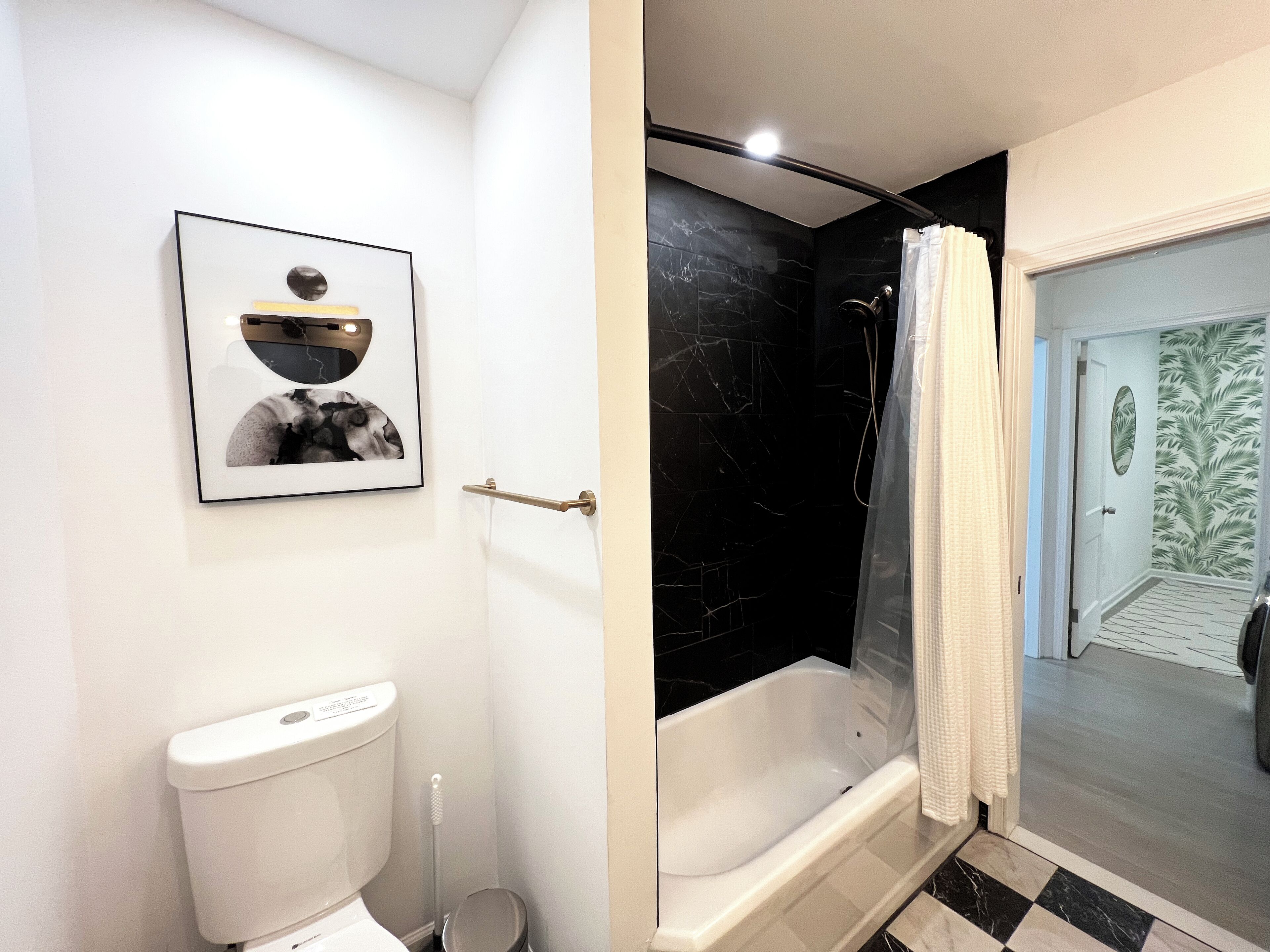 A bathroom with a toilet, a framed picture, a bathtub, and a shower area.