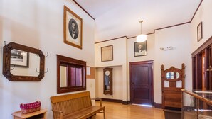 A hallway with wooden flooring, a wooden bench, a small table with a basket, and a mirror on the wall. - Historic High School - Stays and events close to skiing, golf, fishing, hunting! (Kingston)