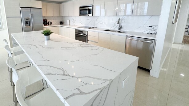 A modern kitchen with a marble island, stainless steel appliances, and a minimalist design. - Exclusive 3 Bedrooms Apartment W/ Amazing View (Hallandale Beach)
