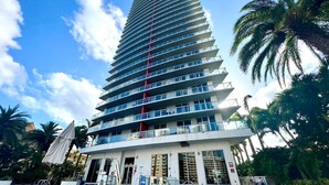 A multi-story hotel with a modern design, featuring balconies on each floor and a pool area in the foreground. - Exclusive 3 Bedrooms Apartment W/ Amazing View (Hallandale Beach)